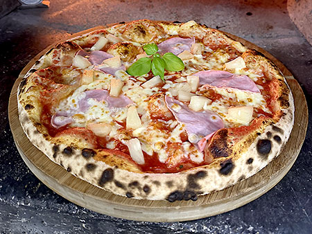 Pizza mit Vorderschinken im Steinofen mit Holzfeuer gebacken